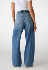 Lichtblauwe, wijde jeans met een hoge taille, voorzien van een aansluitende tailleband en twee achterzakken. Textuur denim stof.