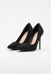 Černé semišové lodičky na vysokém podpatku s špičatou špičkou a štíhlým stiletto podpatkem. Vnitřek je v kontrastní světlé barvě. Hladký povrch a elegantní design.