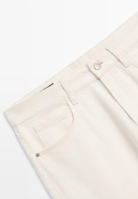Hvide denimjeans med klassisk fem-lomme design, knappelukning og solid syning med en glat, tekstureret finish.