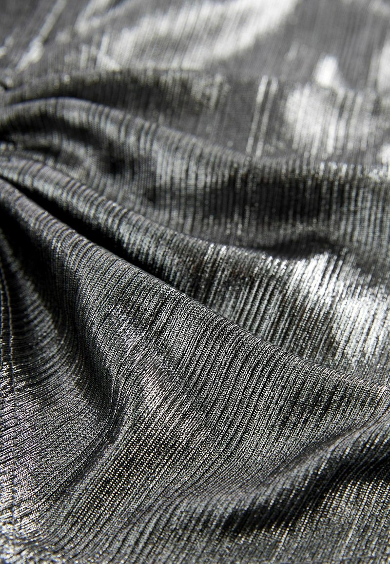 Zwarte metalen jersey-stof met een geribbelde textuur, met een subtiele glans en variërende lichtreflecties over het oppervlak.