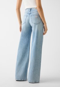 Jasnoniebieskie jeansy o szerokich nogawkach z lekko spranym wykończeniem, wyposażone w klasyczny, pięciokieszeniowy krój oraz naszywkę z logo nad prawą kieszenią.