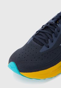 Baskets sportives dotées d'un dessus en maille navy avec perforations, d'une semelle intermédiaire jaune et d'une semelle extérieure texturée turquoise. Comprend des lacets noirs et un détail de logo.