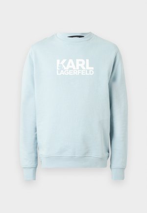 Lyseblå genser med rund hals i mykt stoff, med en markant hvit "KARL LAGERFELD"-logo på fronten. Enkel design, lange ermer.