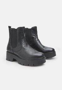 Botines de cuero negro con paneles laterales elásticos y suela de plataforma gruesa. Textura suave con un diseño elegante.