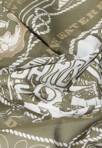 Ύφασμα με εκτύπωση ναυτικής θεματολογίας που απεικονίζει σκοινιά, ψάρια και μερικώς ορατό κείμενο σε αποχρώσεις του απαλού πράσινου, μπεζ και λευκού.