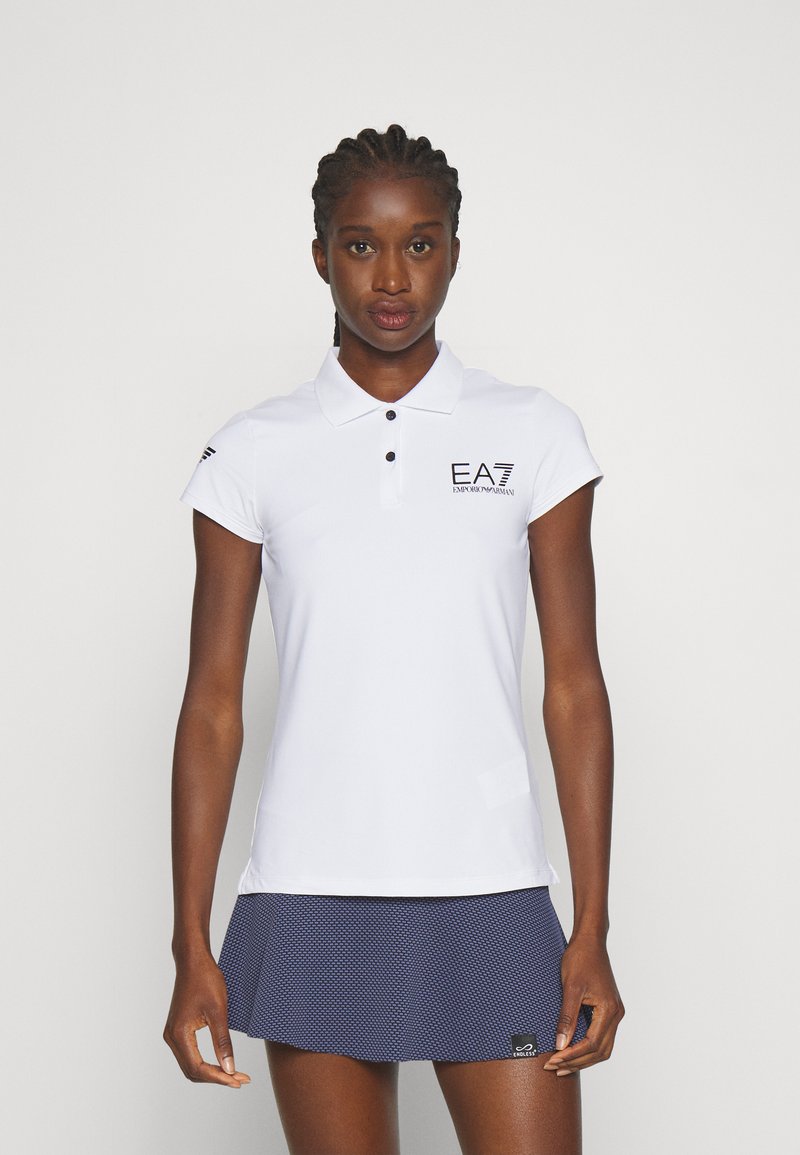 Polo bianco con colletto, maniche corte e logo EA7 nero. Abbinato a una gonna a righe blu scuro. Tessuto morbido e design aderente.