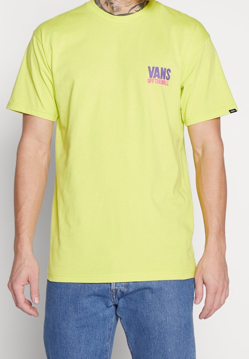 T-shirt en coton vert lime avec un logo "VANS OFF THE WALL" violet et rose sur la poitrine gauche. Manches courtes et encolure ras du cou.