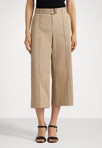 Light beige wide-leg trousers with a belt, featuring subtle seam details and a smooth texture. Paired with black strappy sandals.