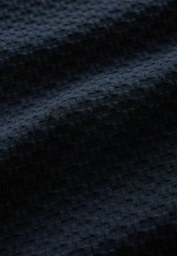 Tissu texturé bleu marine foncé avec un motif de grille subtil, fabriqué à partir d'un matériau doux, présentant une surface lisse et légèrement surélevée.