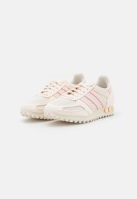 Light pink athletic shoes with mesh and suede upper, featuring three pink stripes, a textured sole, and colorful accents on the heel.