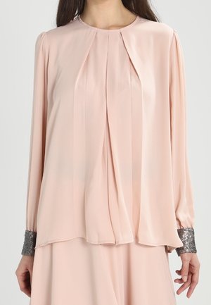 Lyserød bluse med lange ærmer, der har lodrette læg og sølv-accenterede manchetter. Glat stof og rund halsudskæring.