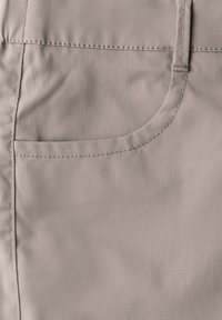Beige Stoff mit glatter Textur und subtiler Sheen, mit einer gebogenen Tasche und gesteppten Details entlang der Kanten.