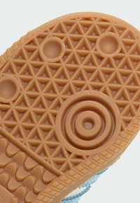 Guma obuv s podrážkou so štruktúrovaným, včelím vzorom a kruhovými a trojuholníkovými dizajnmi. Farba je svetlohnedá s hladkým povrchom.