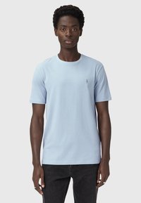 Lys blå kortærmet t-shirt i blødt stof med rund halsudskæring og lille broderet detalje på brystet. Sammen med mørke jeans.