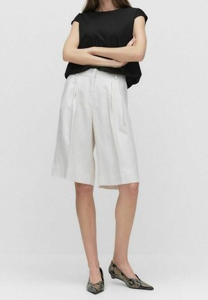 Hvide linnedshorts med plisseringer og høj talje, kombineret med en sort kortærmet top og sko med slangeprint. Enkel, afslappet pasform.