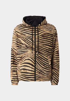 Hættejakke i et beige og sort tigerstribes mønster, med en lynlås foran, elastiske manchetter og et logo på venstre side.