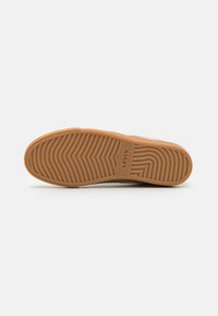 Levi's sneaker talpája, amely gumi anyagból készült, hullámos mintával, bézs színben és dombornyomott logóval. Sima tapintású, csúszásgátló vonalakkal.