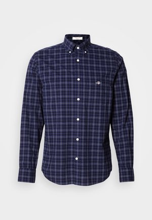 Men’s long-sleeve button-up shirt with navy blue, black, and white checked pattern, buttoned collar, and chest logo on left side.