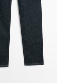 Jeans in denim blu scuro con design a gamba dritta, cuciture visibili e orlo pulito. Il materiale presenta una texture minima.