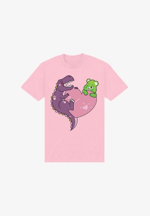 Pink t-shirt med et tegneserieagtigt lilla dinosaur og en grøn bjørn, begge med smilende ansigtstræk, mod en lys pink baggrund.