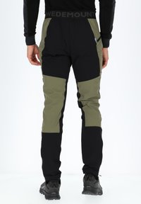 Zwarte en olijfgroene broek met een slim fit ontwerp. Bevat grote panelen, een elastische tailleband en een blauwe accentlabel. Textured stof.