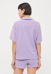 Set di abbigliamento da casa a righe viola composto da un tessuto morbido; presenta una maglietta corta con colletto e pantaloni corti abbinati.