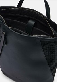 Czarna skórzana torba na ramię z teksturowaną siateczkową boczną częścią, zamykanymi kieszeniami i wnętrzem z kieszeniami. Gładkie wykończenie i zintegrowane uchwyty.