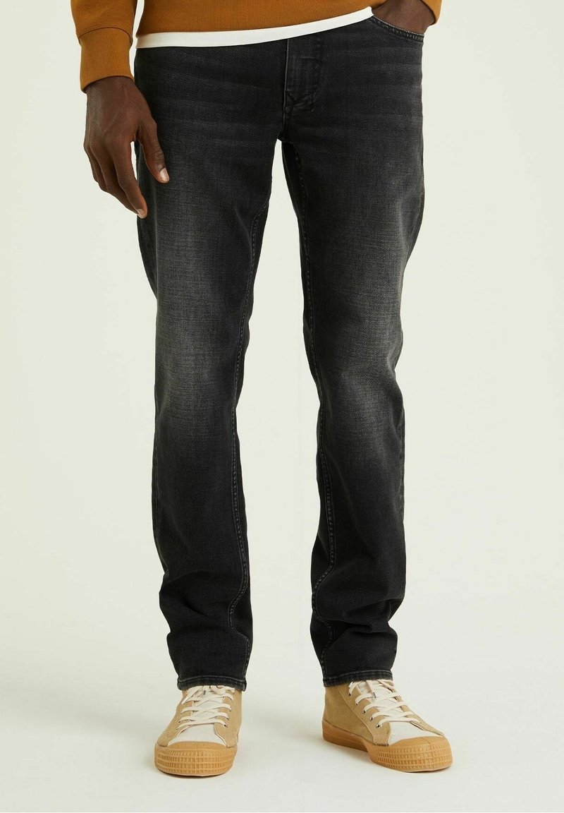 Svarta denimjeans med raka ben, subtila urtvättningar, femfickorsdesign och ljusbruna snörskor med gummisula.