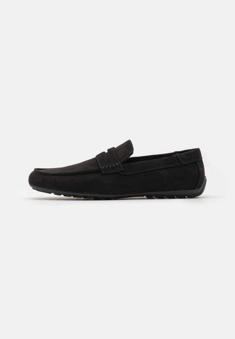 Mocassin homme en daim noir avec semelle en caoutchouc et détail de bride décorative, présenté de profil sur fond blanc.