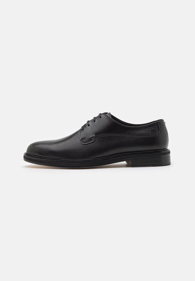 Chaussure formelle en cuir noir à lacets, finition lisse et talon bas, montrée de profil sur un fond clair uni.