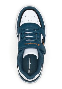 Zapatilla deportiva en color azul verdoso y blanco con cierre de cordones y velcro. Presenta una puntera perforada, un collar acolchado y un detalle del logo en el lateral.