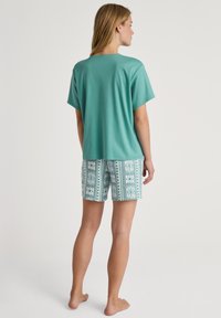 Lichtblauwe katoen T-shirt met korte mouwen, gecombineerd met gestreepte blauwe shorts met ingewikkelde patronen en een relaxte pasvorm.