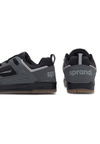 Czarne i szare buty sportowe z siateczkowymi akcentami, wyściełanym kołnierzem i gumową podeszwą. Posiadają branding na pięcie i boku.