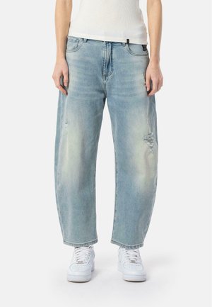 Lichtblauwe denim jeans met een losse pasvorm, beschadigde details en een klassiek vijf-pocket ontwerp, gecombineerd met witte sneakers.