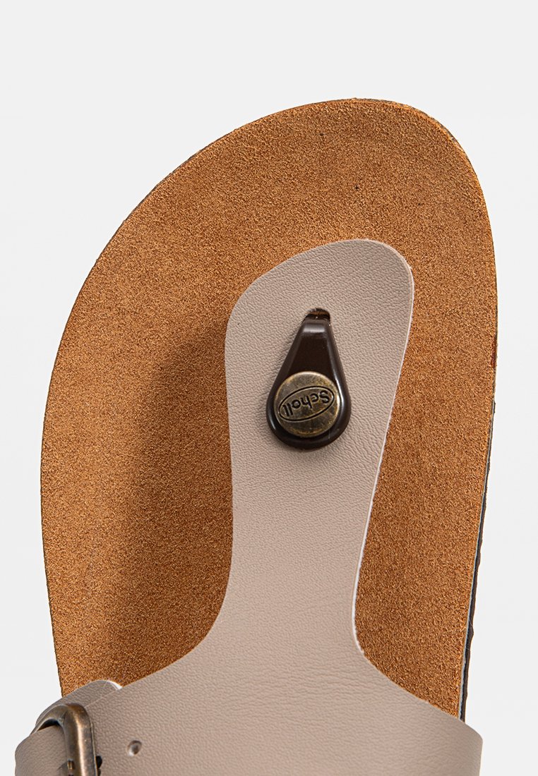 Sandale réglable beige dotée d'une semelle en liège rembourrée, d'une sangle en cuir marron et d'un détail en bouton marron foncé pour une fermeture sécurisée.