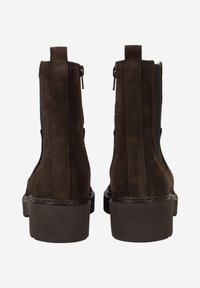 Brown suede ankle boots with a chunky sole, featuring zipper closures and elastic side panels, showcasing a sleek and minimal design.