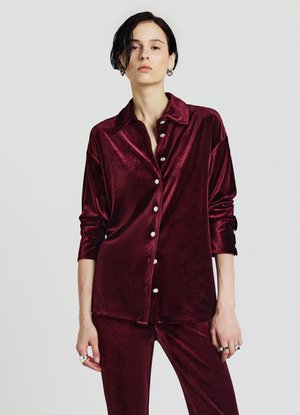 Camicia di velluto borgogna con maniche lunghe, colletto a punta e chiusura frontale con bottoni decorativi, abbinata a pantaloni coordinati.