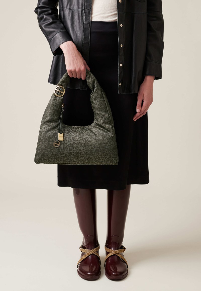 Green textured handbag with a hobo shape, featuring a top handle, gold hardware accents, and a zip closure, held by a person.