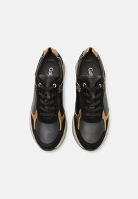 Baskets en cuir noir et or avec lacets noirs et semelles beiges, avec un motif léopard sur le talon.