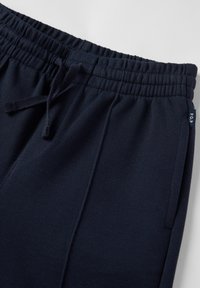 Marineblauwe sportbroeken van een textured stof, met een elastische tailleband, verstelbaar trekkoord en zijzakken. Opvallend merkembleem weergegeven.