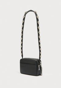 Μαύρη τσάντα ώμου με υφή, κλείσιμο με φερμουάρ και διακοσμητικό λουράκι με κυκλικά ασημένια διακοσμητικά.