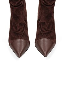 Stivaletti in suede marrone con punta appuntita e cap toe in pelle. Il materiale appare morbido con una finitura testurizzata. Design elegante e slanciato.