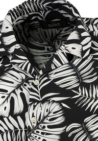 Camisa de manga corta abotonada en tejido negro con patrones de hojas blancas, que cuenta con un cuello y un cierre de botones en la parte delantera.