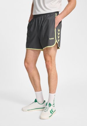 Zwarte sportshorts met gele bies, zijzakken en een chevronpatroon. Gemaakt van lichtgewicht materiaal, ontworpen voor comfort.