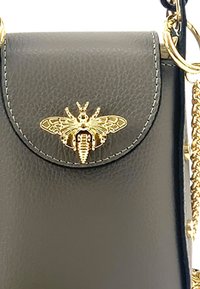 Zwarte leren tas met een textuurafwerking, voorzien van een gouden bijembleem op de klepsluiting, geaccentueerd met gouden kettinghardware.