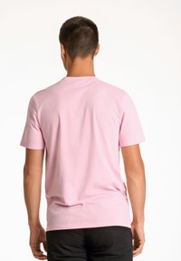 Kortärmad rosa T-shirt i bomull, med rund hals och avslappnad passform, synliga sömmar längs ärmarna och nedre fållen.