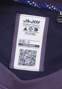 Marine stoffen label met een wit etiket met zwarte tekst, een QR-code en decoratieve geweven accenten in paars en bruin. De tekst bevat het merk en de locatie.
