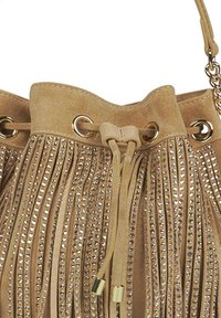 Bolso de cubo de ante marrón con flecos decorativos, adornado con tachuelas plateadas. Cuenta con herrajes en tono dorado y un cierre de cordón.