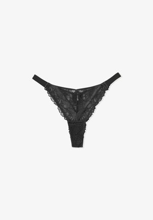 Tanga de encaje negro con patrón floral, con borde en forma de ondas y una cinturilla elástica suave. Diseño delicado y transparente.