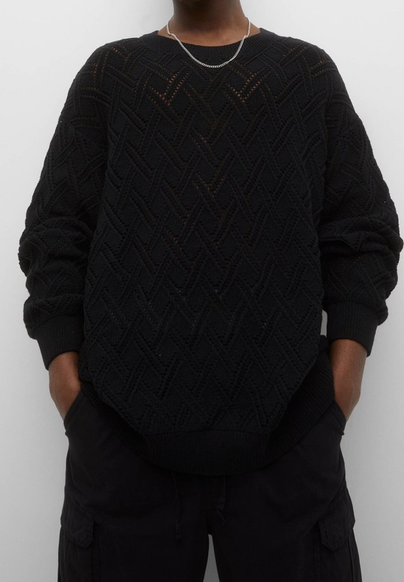 Zwart gebreide trui met een gestructureerd, geweven patroon, geribbelde boorden en zoom. Losvallende pasvorm met verlaagde schouders en lange mouwen.